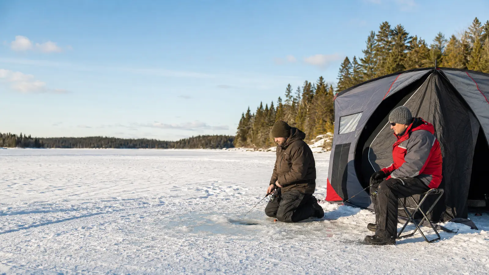 Two anglers fish beside a portable shelter on a frozen Ontario lake.